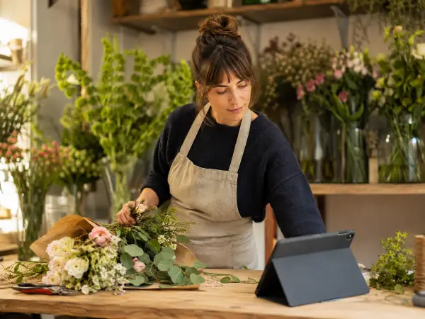 Fleuriste consultant une tablette dans son atelier floral